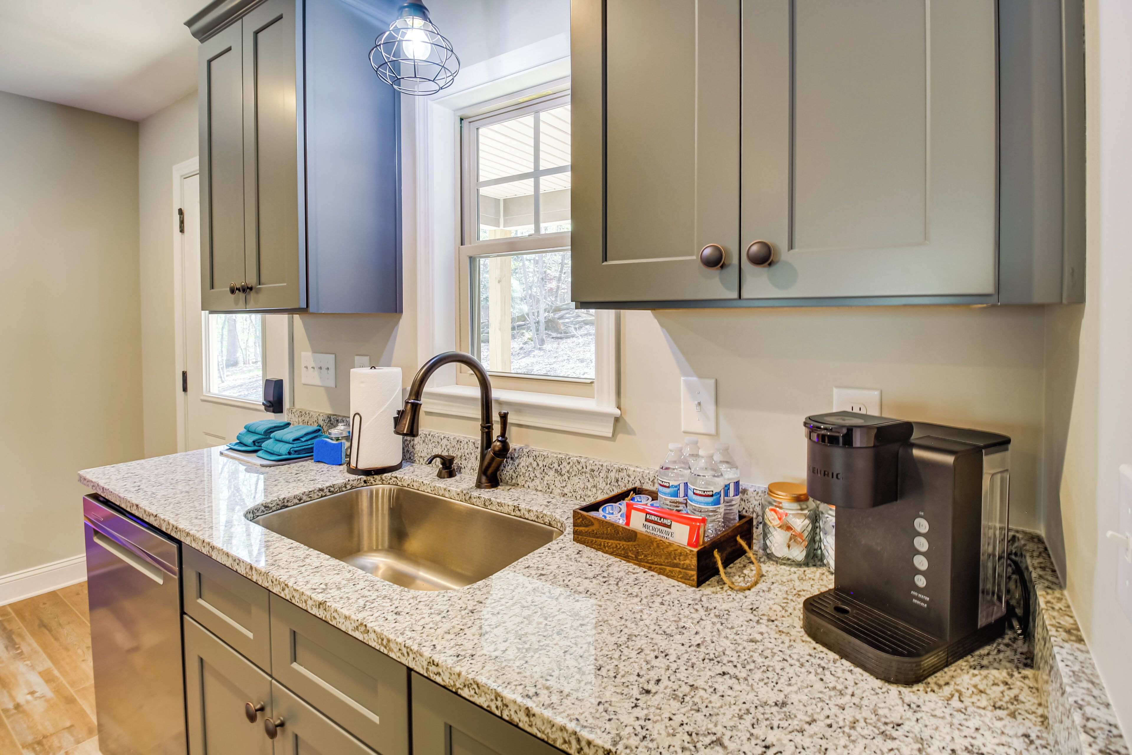 A kitchen with granite countertops, stainless steel sink, and a coffee maker.