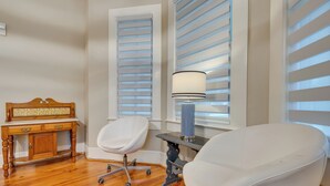 Une pièce avec un bureau en bois, deux chaises blanches, une lampe et un radiateur.