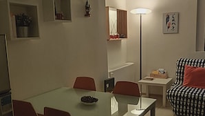 A dining area with a glass table, red chairs, and a sofa with a patterned cover. - Gemme Fiorentine Martina apartment free parking 5 minutes from centre by train  (Firenze)