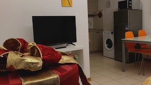A living room with a red and gold ottoman, a flat-screen TV, and a staircase leading to an upper level. - Gemme Fiorentine Martina apartment free parking 5 minutes from centre by train  (Firenze)