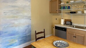 A kitchen with a wooden table, a dishwasher, and a shelf with dishes and a toaster. -  Historic Waterfront District., for lovers of art, restaurants, unique shops, 

 (Warren)