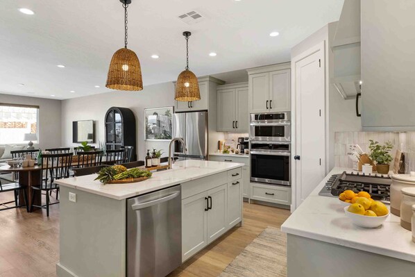 A modern kitchen with white cabinets, stainless steel appliances, and a central island with fresh produce.