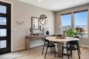 A modern dining area with a round table, black chairs, and a wooden bench.