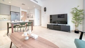 Een moderne woonkamer met een houten eettafel, een flatscreen televisie en een potplant.