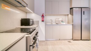 Een moderne keuken met een magnetron, fornuis, oven, spoelbak en een roestvrijstalen koelkast.
