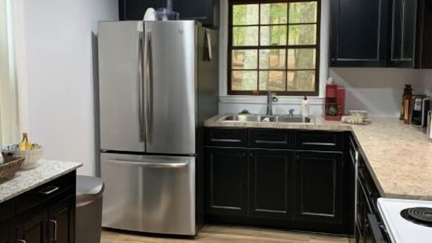 Una cocina moderna con gabinetes oscuros, un refrigerador de acero inoxidable, una ventana y un lavamanos.