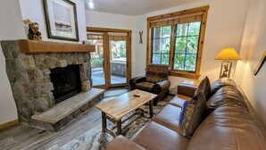 A cozy living room with a stone fireplace, leather sofa, and a coffee table. - River Run Summer Fun | Patio, Pool  & Hot Tub (Keystone)