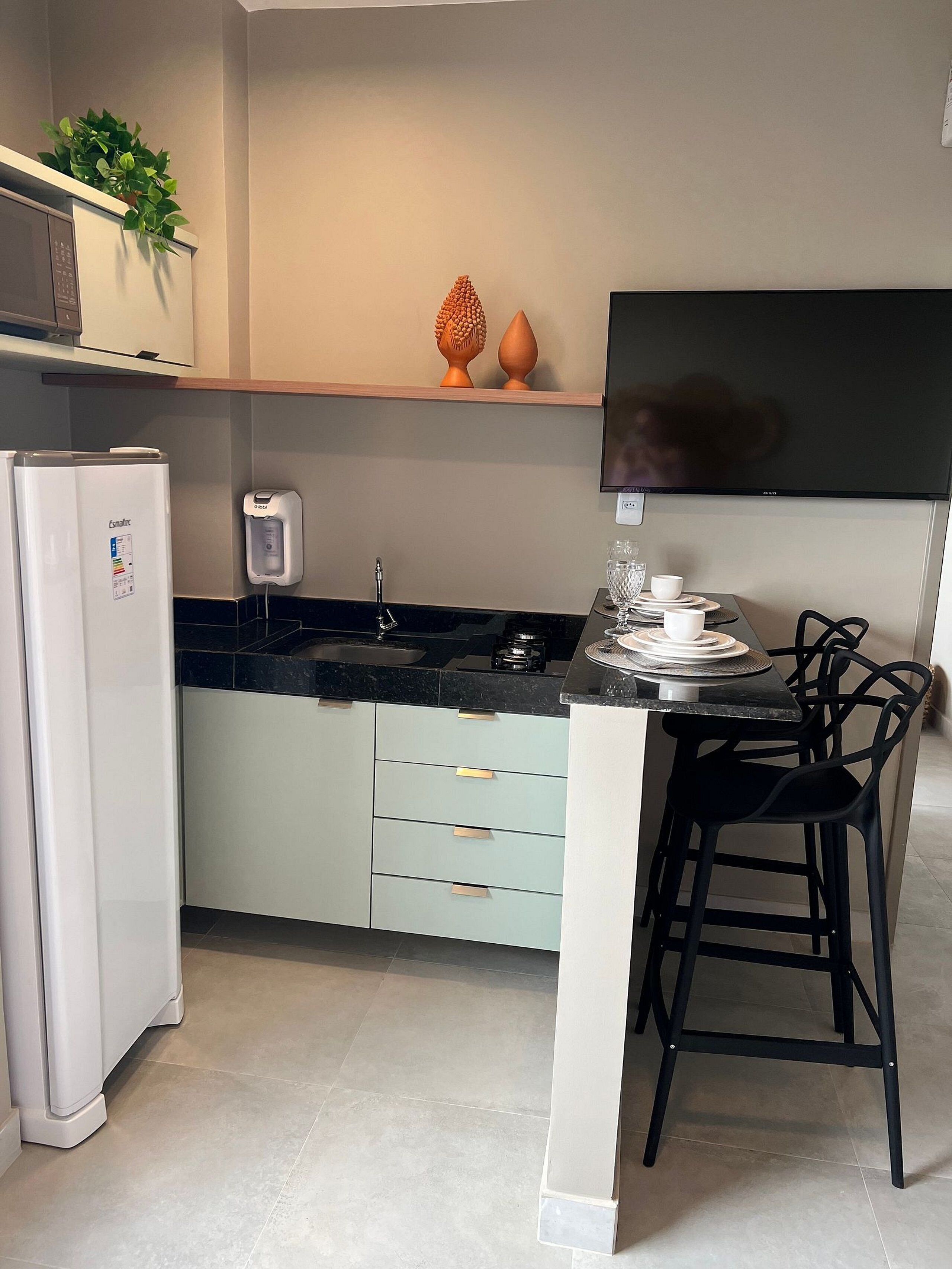 A modern kitchen with a built-in refrigerator, a microwave, a coffee machine, and a dining area with two black chairs.