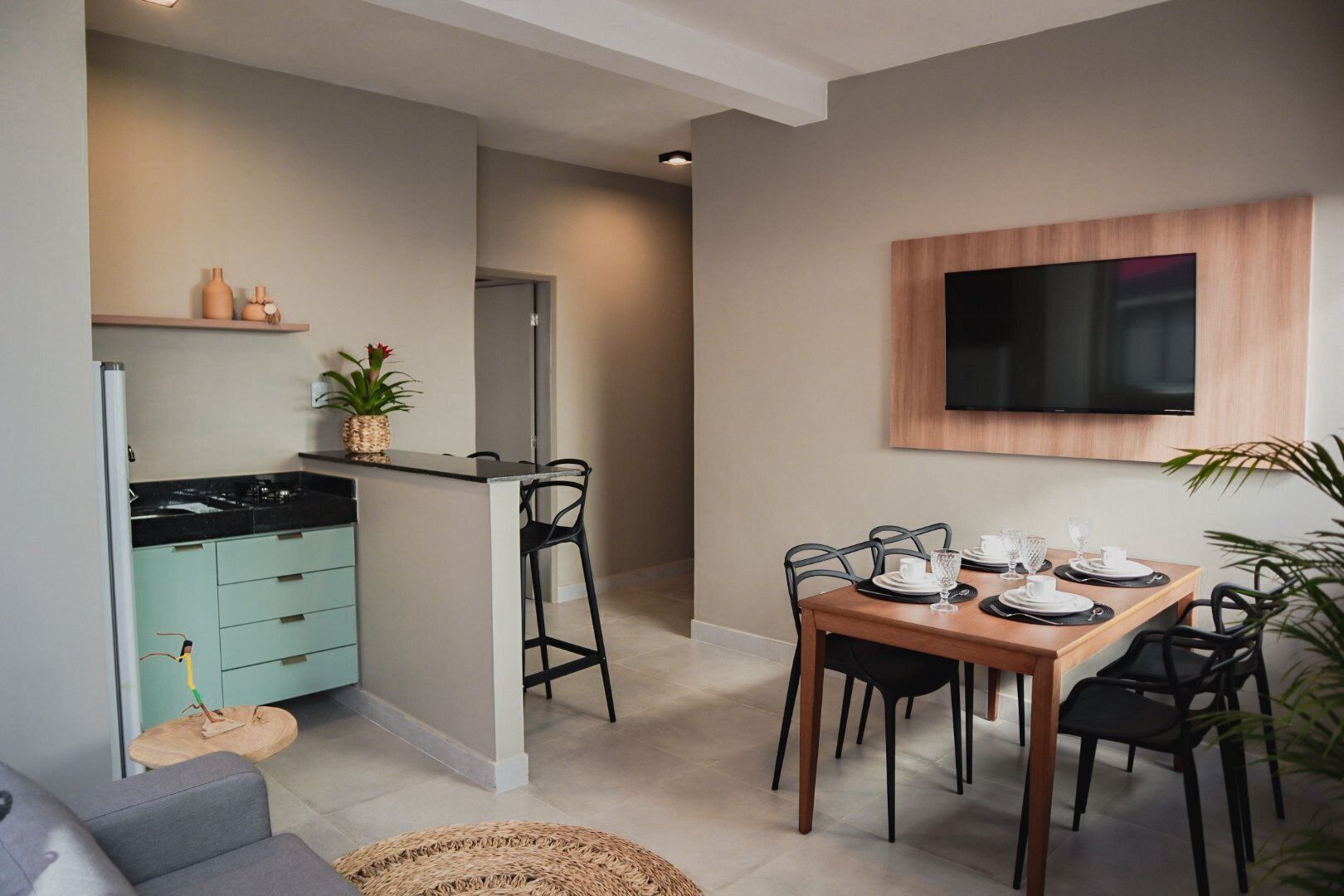 Una cocina moderna con comedor, un televisor montado en la pared y una planta pequeña en la encimera.