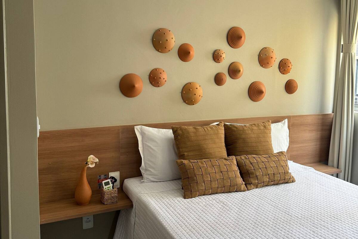 Ein Hotelzimmer mit einem großen Bett, einem hölzernen Kopfteil und einer Wand mit runden Dekorationselementen.