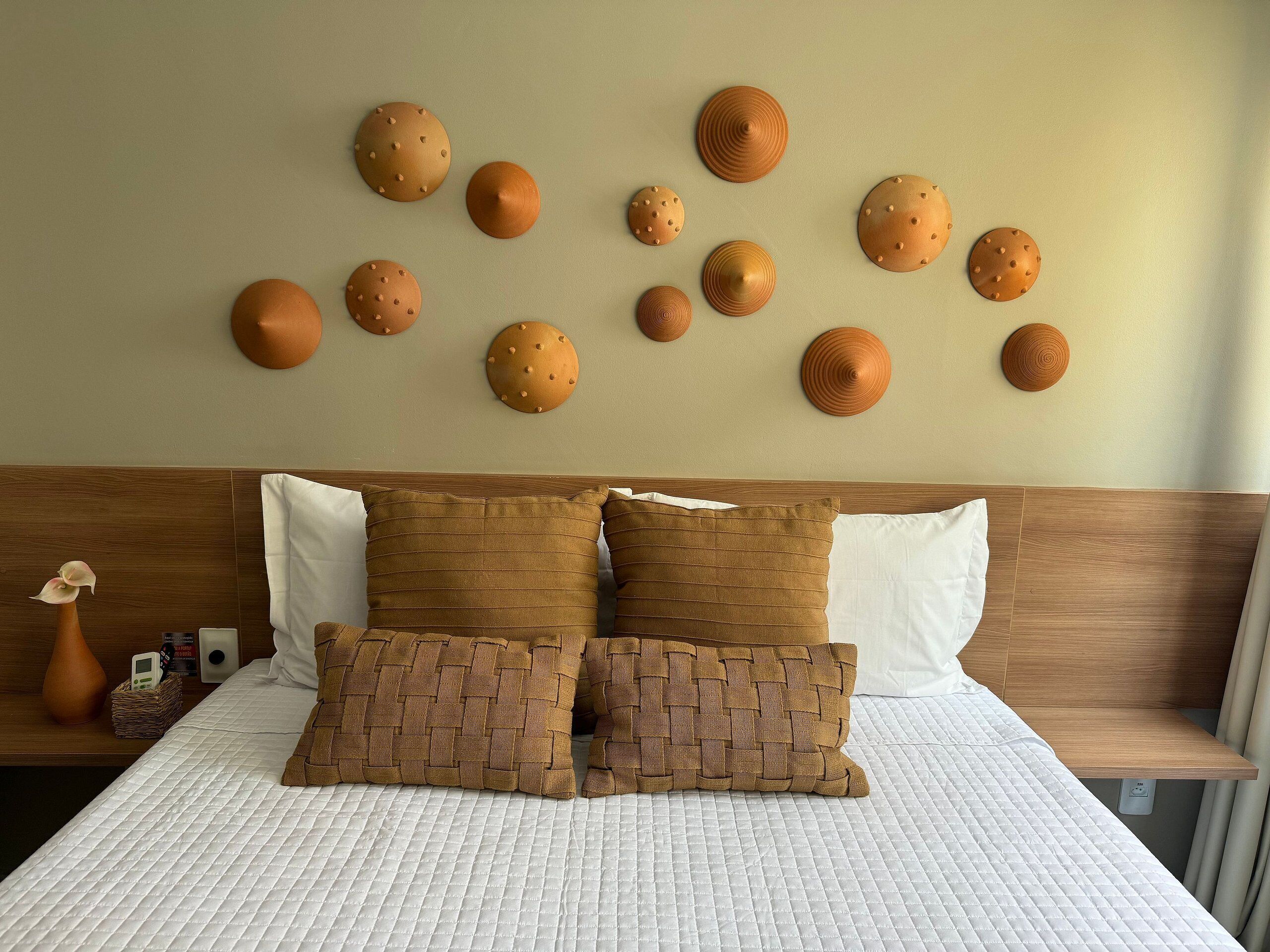 A neatly made bed with a white quilted bedspread, two brown woven pillows, and a wooden headboard.
