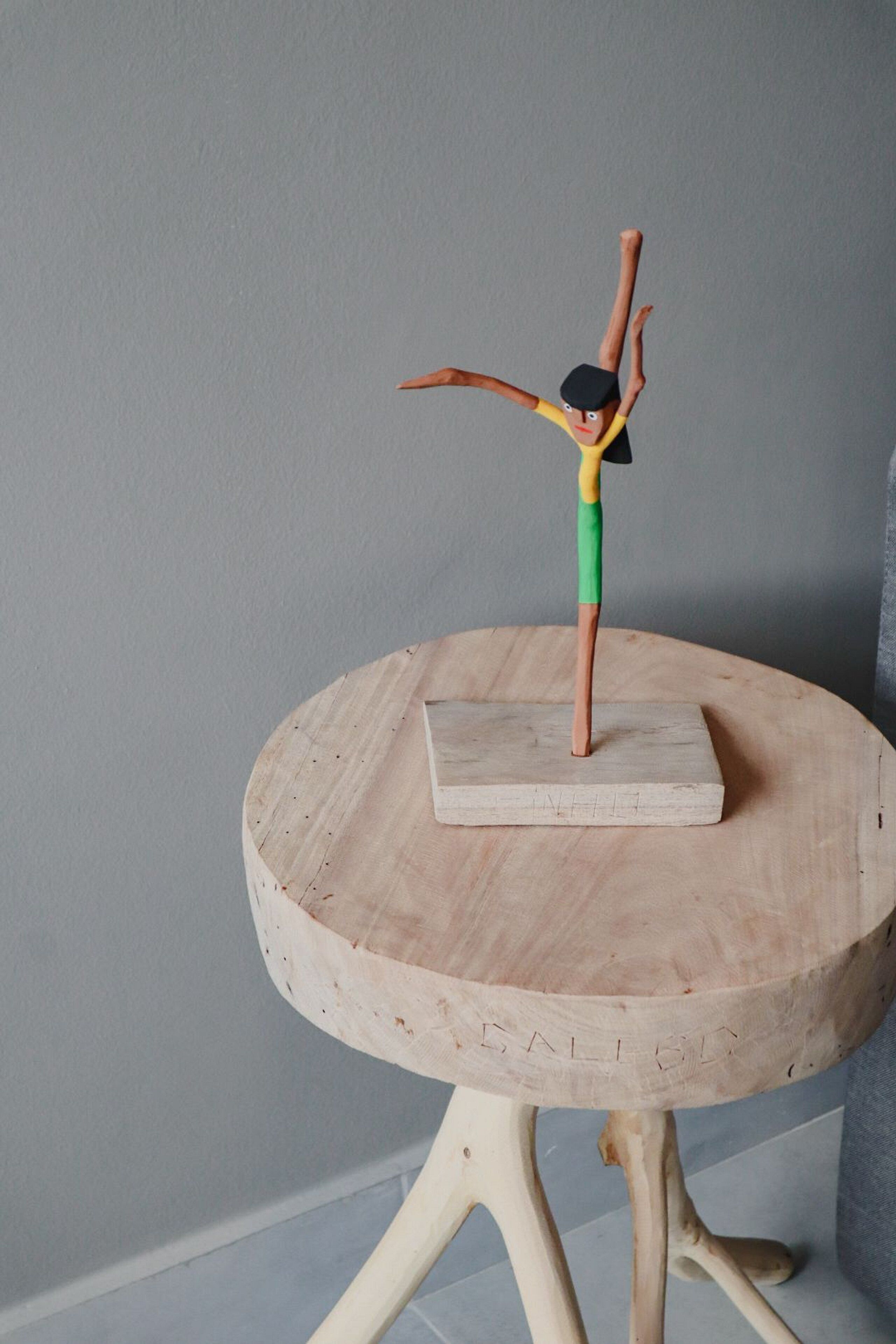 A wooden table with a small sculpture of a figure on top.