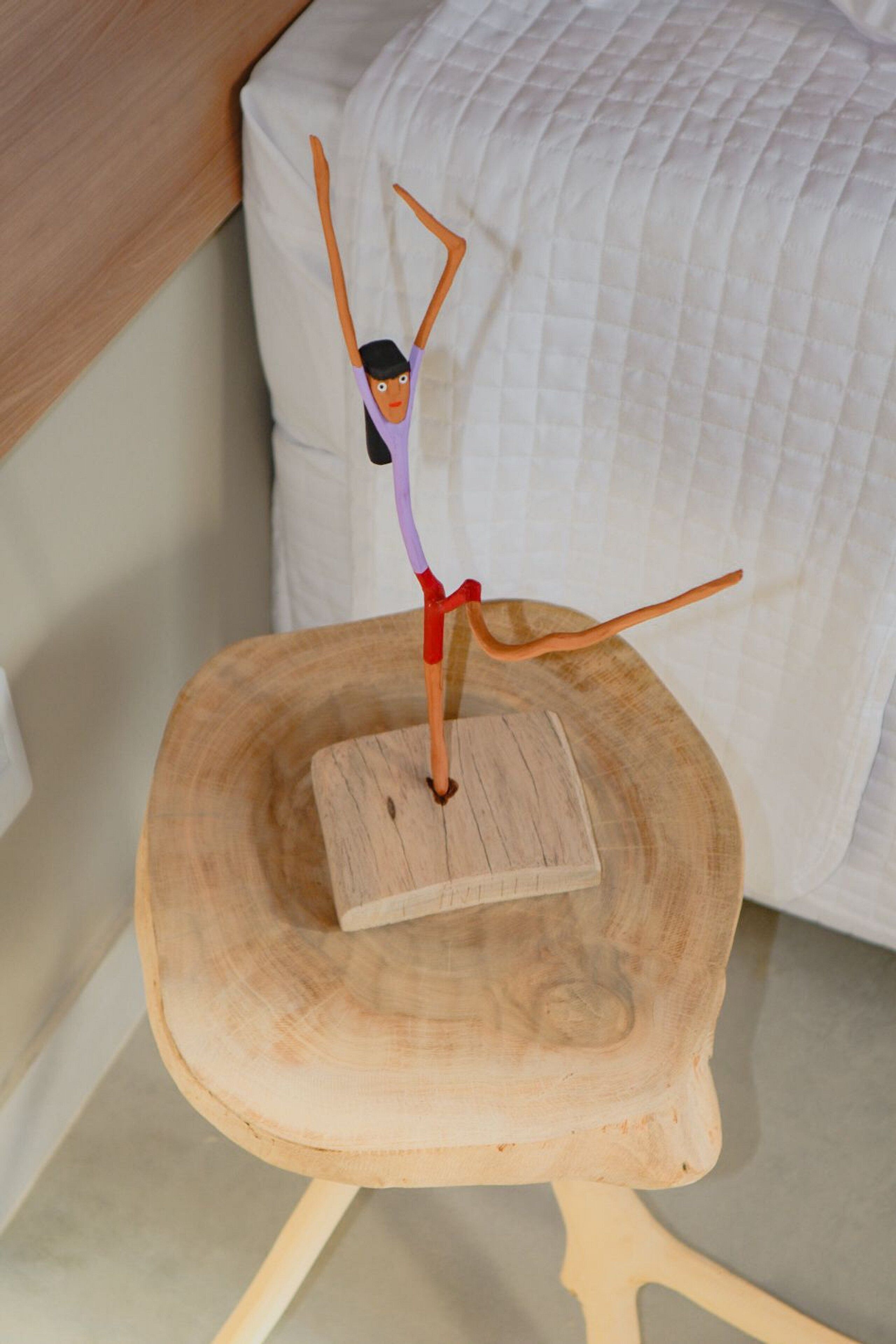 A wooden table with a figure of a person in a purple top and red skirt, standing on a square platform.