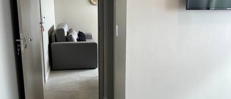 Habitación de hotel con cama, televisor montado en la pared y puerta que da a otra habitación.