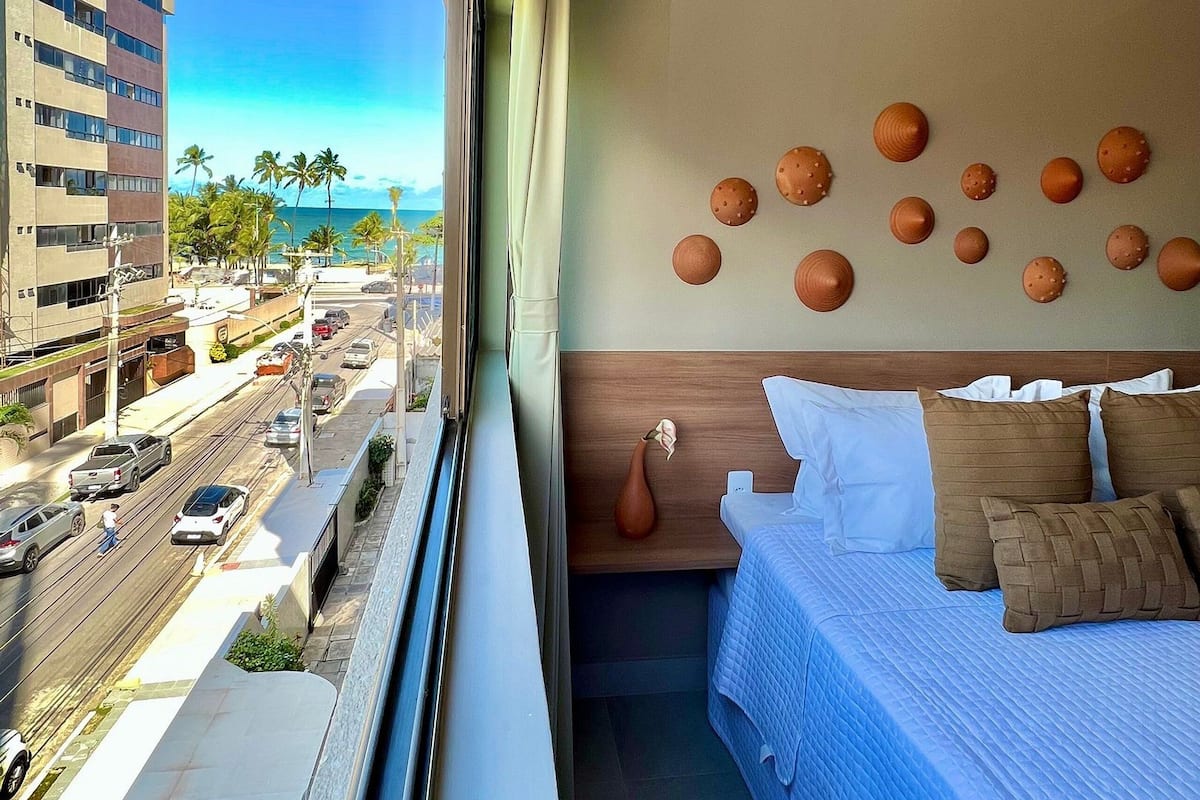 Ein Hotelzimmer mit Blick auf die Stadt, ein Bett mit Kissen, eine Vase und eine Wand mit dekorativen Tellern.