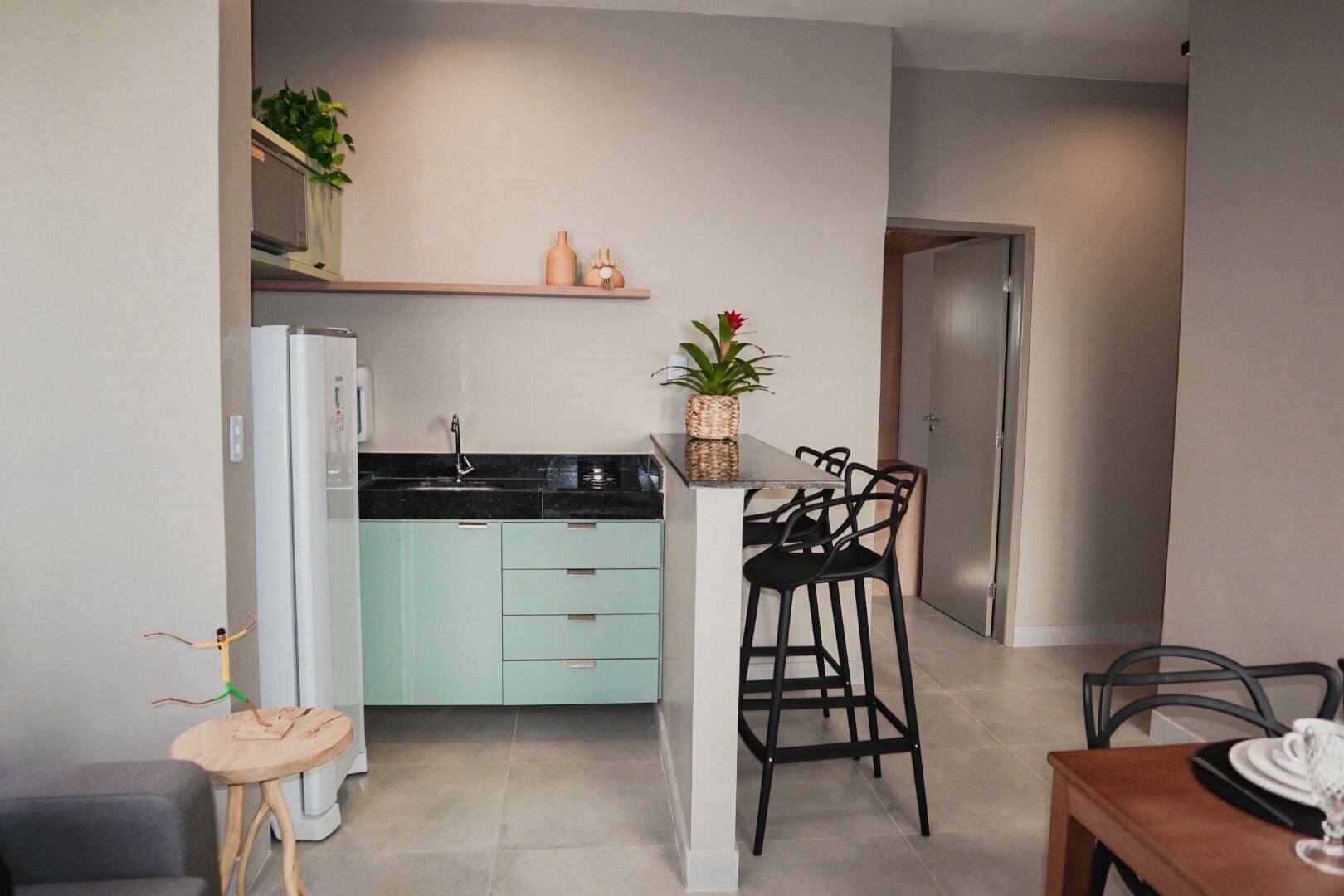 A compact kitchen with a refrigerator, sink, and a small dining area with two chairs and a table.
