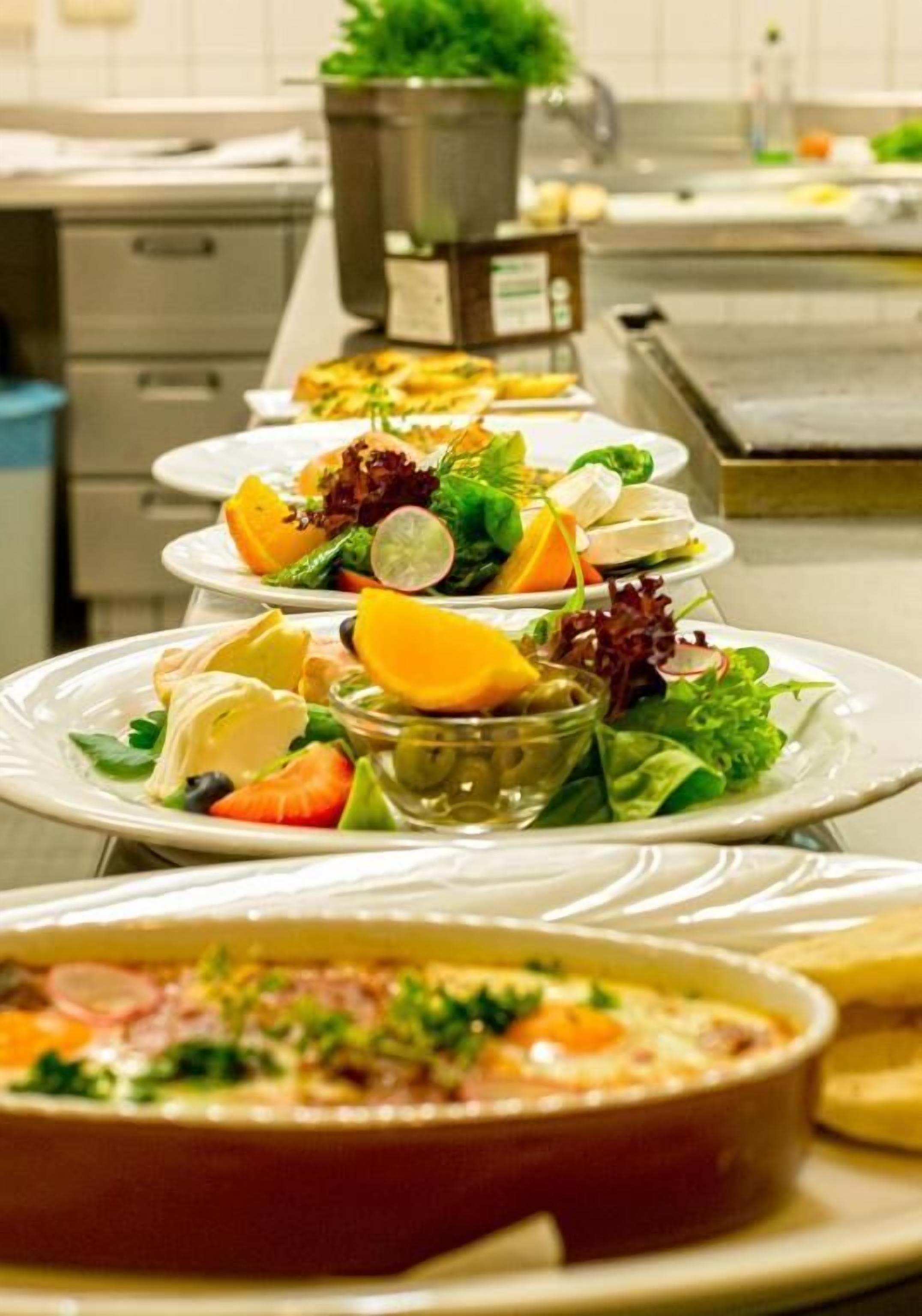Ein reichhaltiges Buffet mit verschiedenen Speisen, darunter Salate, Früchte und ein Auflauf.