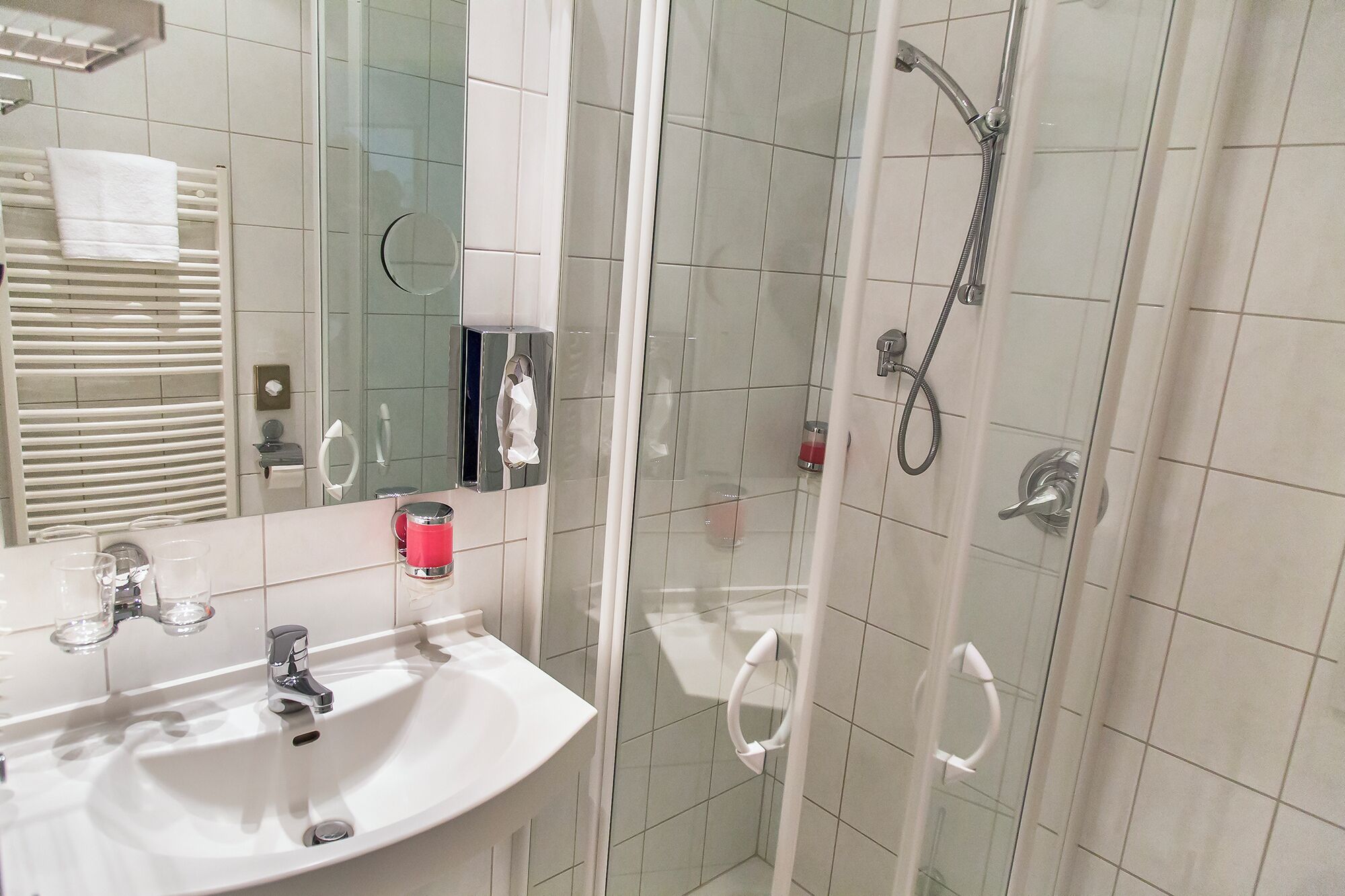 A bathroom with a white sink, a glass shower enclosure, and a mirror.