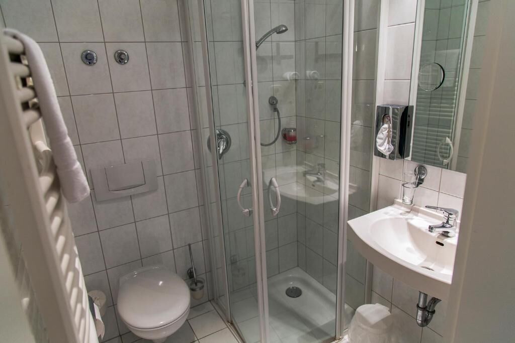 Une salle de bain moderne avec une douche à parois de verre, des toilettes blanches et un lavabo avec un miroir.