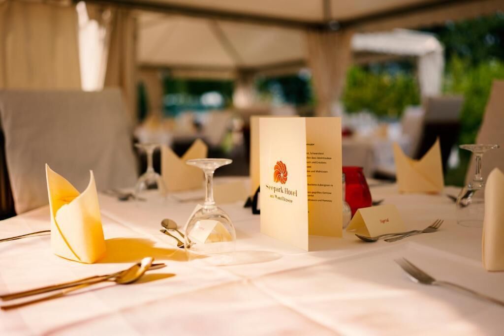 Una mesa lista para comer, con un menú, un vaso y cubiertos.