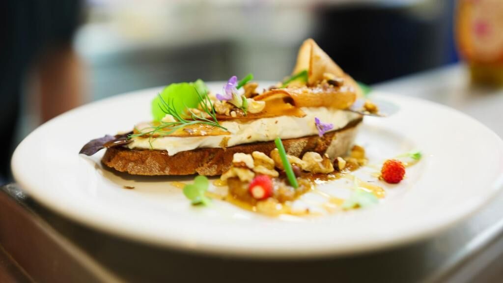 A plate with a layered food item, garnished with herbs and small fruits.