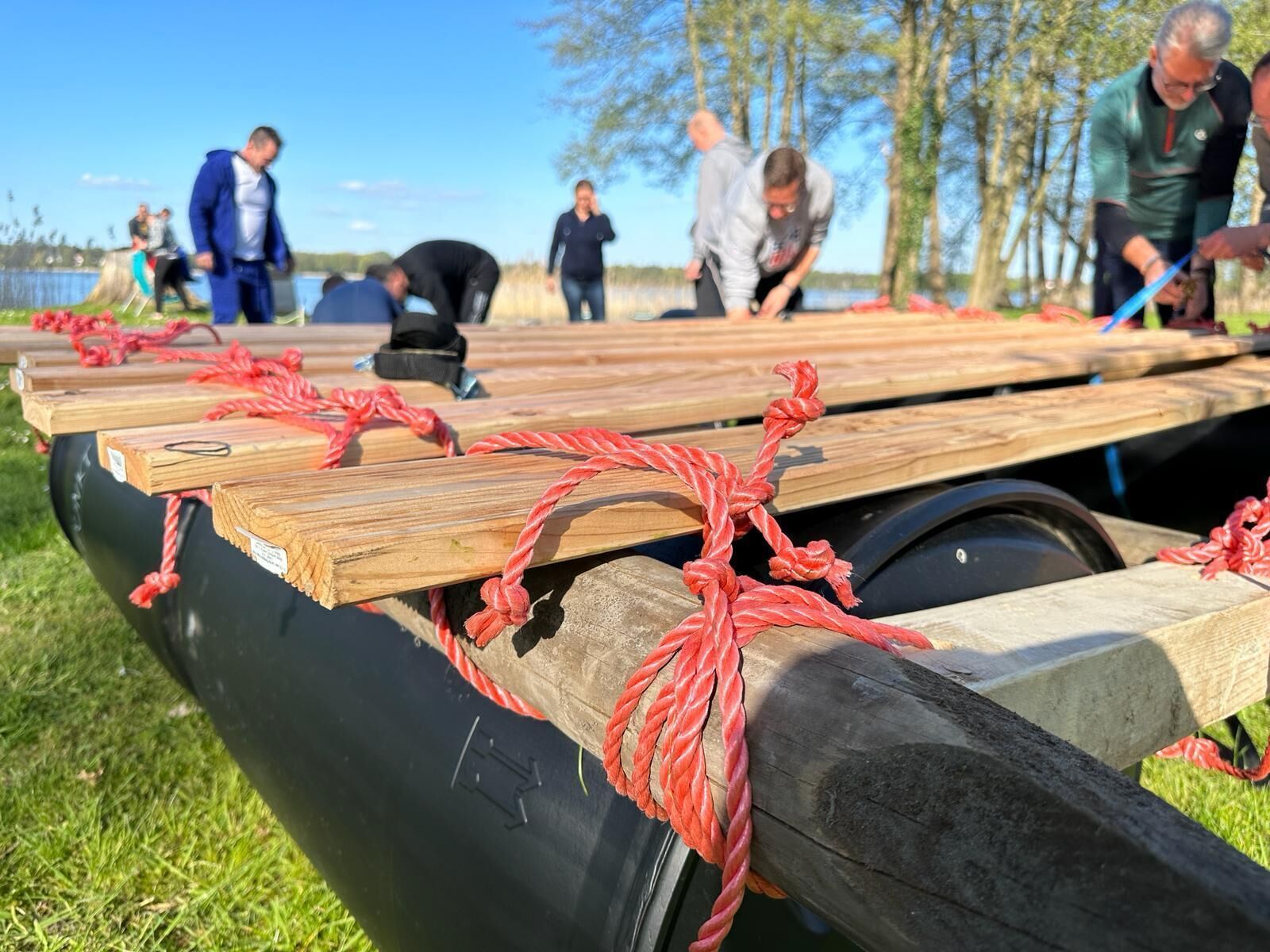 Un bote con casco negro y cubierta de madera, asegurado con cuerdas rojas.