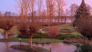 A paved pathway with a circular brick pattern, surrounded by trees and shrubs, leading towards a body of water. - Seepark Hotel am Wandlitzsee (Wandlitz)