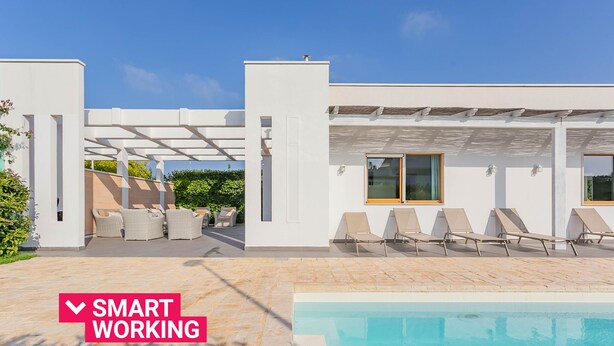 Ein moderner Poolbereich im Freien mit Liegestühlen und einer Pergola.