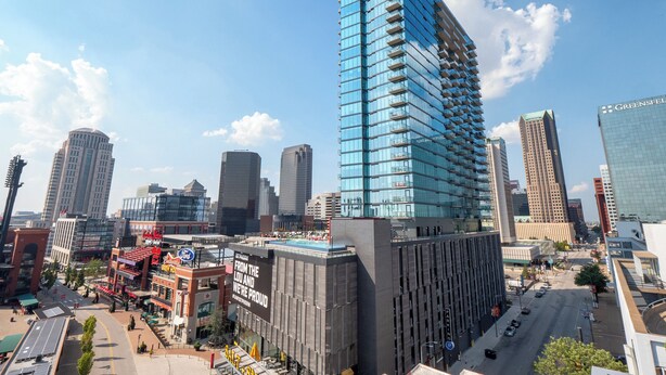 A modern high-rise building with a glass facade, surrounded by other tall buildings in a cityscape. - Ballpark Luxury Loft Steps from Arch (St. Louis)