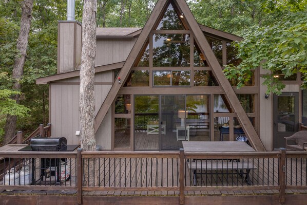 Une cabane avec une façade en bois, de grandes fenêtres et une terrasse dotée de meubles d’extérieur.