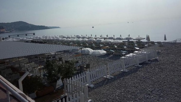 Une plage avec des parasols et une clôture blanche.