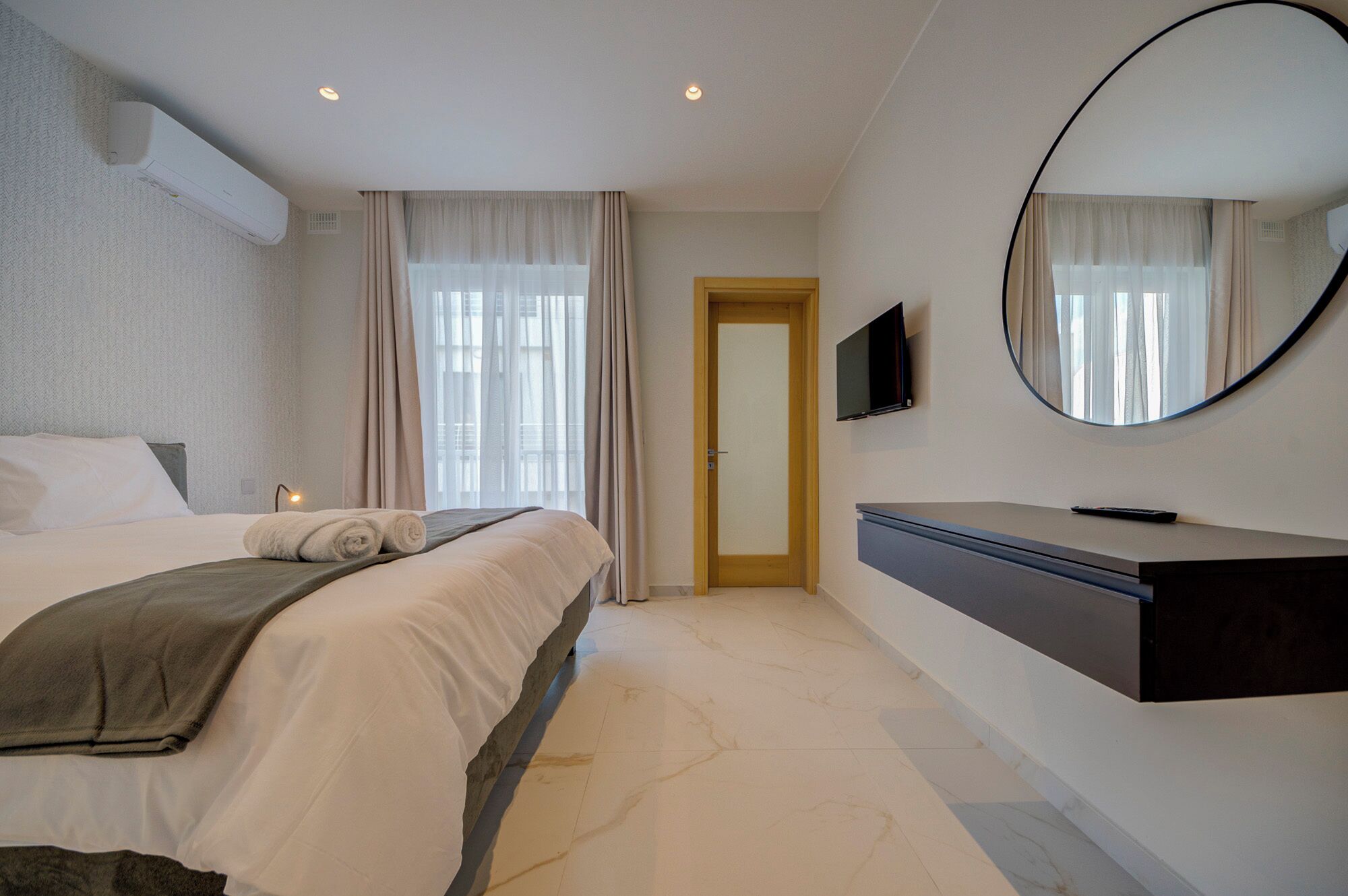 Una habitación de hotel con cama, televisión, espejo y puerta.