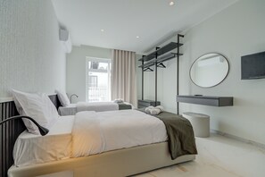 A modern hotel room with a large bed, a bedside table, a mirror, and a view of the outside.