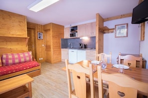 A cozy room with a wooden sofa, a dining table with chairs, and a kitchenette. - Ground floor, terrace, tv, ski locker, 29m², Aussois (Aussois)