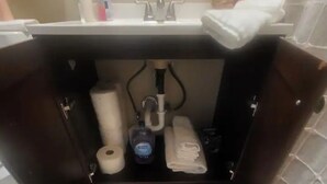 A bathroom sink with a mirror above it, a towel rack, and toiletries.