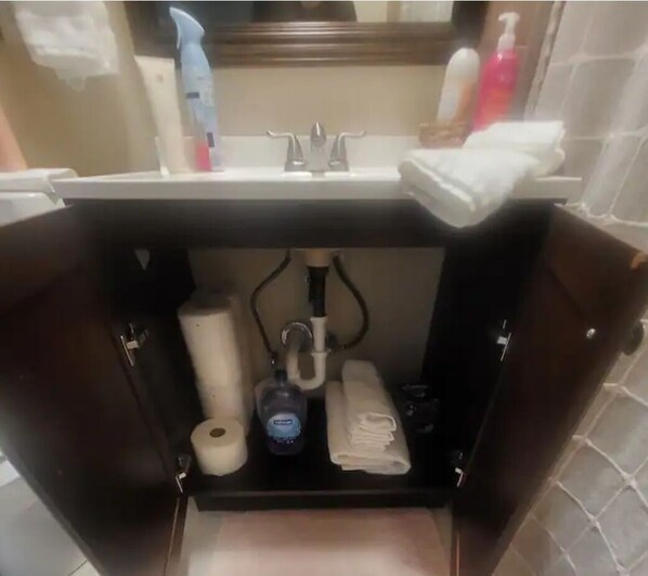 Un lavabo dans la salle de bain, avec un miroir au-dessus, un porte-serviettes et des articles de toilette.