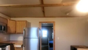 A compact kitchen with wooden cabinets, a stainless steel refrigerator, and a wooden countertop.