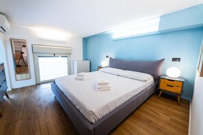 A bedroom with a large bed, bedside tables, a wardrobe, and a door leading to a balcony. - Loft Porta Maggiore - Three Bedroom Apartment, Sleeps 6 (Rome)