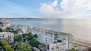 Un paysage urbain côtier avec des bâtiments modernes, une plage et un ciel dégagé.