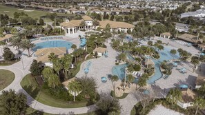 Vista aérea de un complejo turístico con múltiples piscinas, palmeras y un pabellón central.