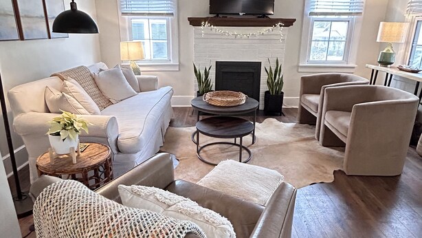 A living room with a sofa, armchairs, a coffee table, and a fireplace.