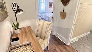 A dining area with a wooden table, a chair, a potted plant, and a wall-mounted lamp.