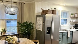 A modern kitchen with a stainless steel refrigerator, wooden dining table, and a potted plant.