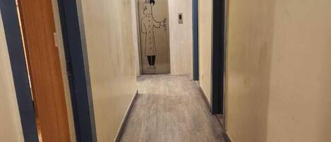 A hallway with wooden flooring and beige walls.