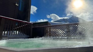 A hot spring area with a wooden deck and a view of mountains in the background. - Rustic Retreat - Mt Crested Butte (Crested Butte)