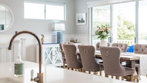 Une cuisine moderne avec un plan de travail blanc, un évier et une fenêtre donnant sur un balcon.