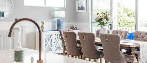Een moderne keuken met een wit aanrecht, een spoelbak en een raam met uitzicht op een balkon.