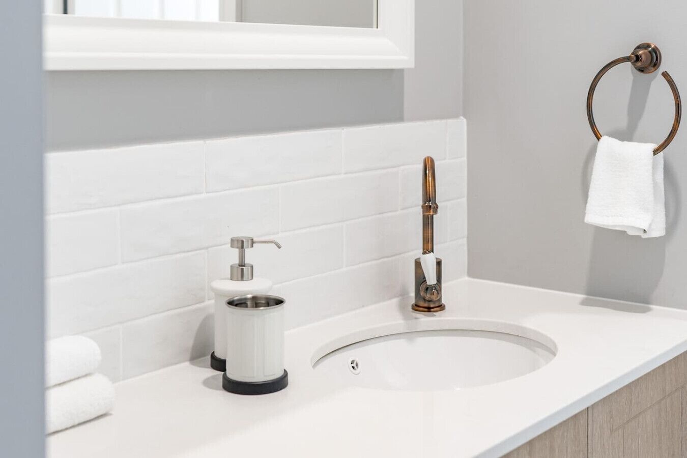 Un bagno con un lavandino bianco, un erogatore di sapone e un portasciugamani.