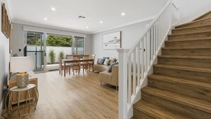 Un vaste espace de vie comprenant un escalier en bois, une table à manger avec des chaises et un canapé.