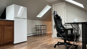 A compact kitchen with a white refrigerator, a dining table with a chair, and a skylight above. - Cute & Cozy Providence Studio! (Providence)